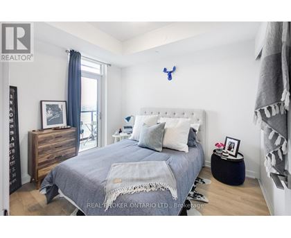 A bedroom with a bed, nightstand, and a dresser with a mirror.