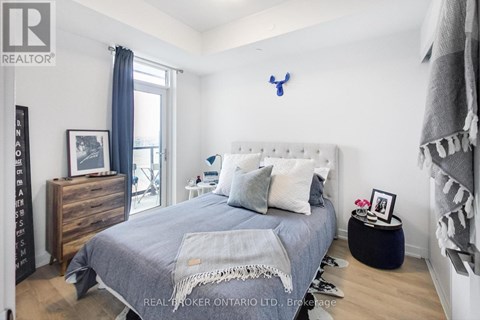 A bedroom with a bed, nightstand, and a dresser with a mirror.