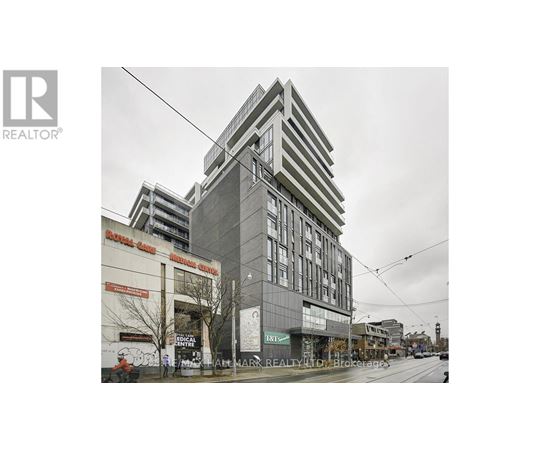 A tall building with a grey facade stands in the middle of a street.