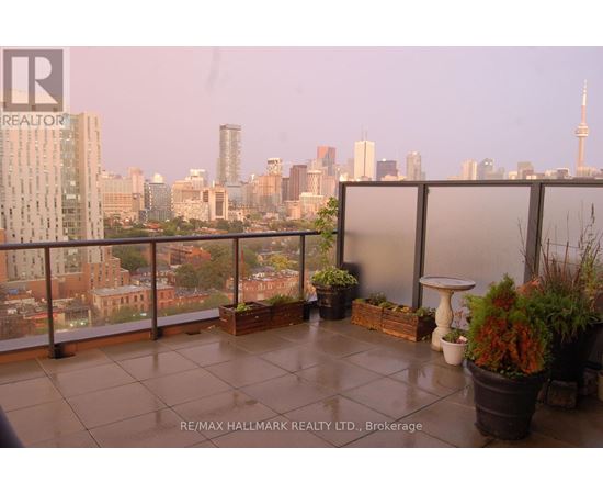A balcony with potted plants and a table overlooking a city skyline.