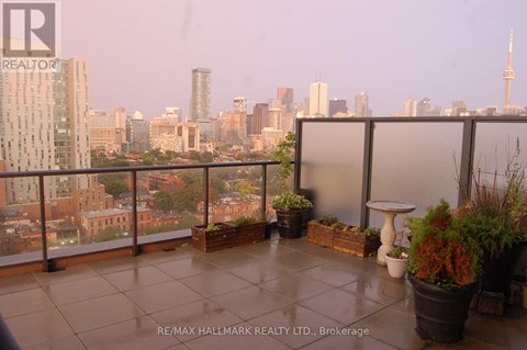A balcony with potted plants and a table overlooking a city skyline.