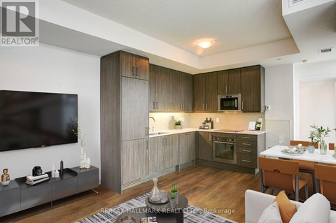 A modern kitchen with wooden cabinets and a TV mounted on the wall.