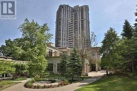 A large building with a tall tower is surrounded by trees and a well-maintained lawn.