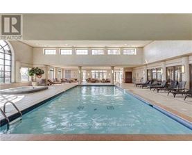 A large indoor swimming pool with lounge chairs and a plant.