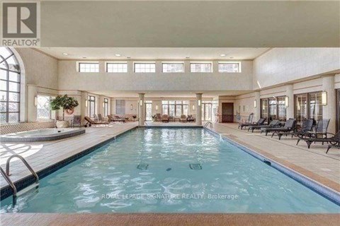 A large indoor swimming pool with lounge chairs and a plant.