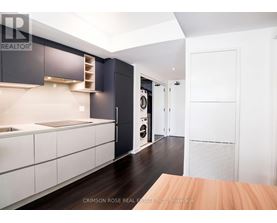 A modern kitchen with dark wood floors and white cabinetry.