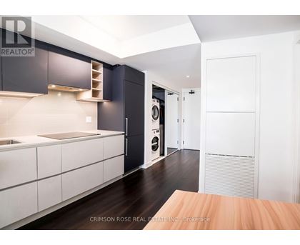 A modern kitchen with dark wood floors and white cabinetry.