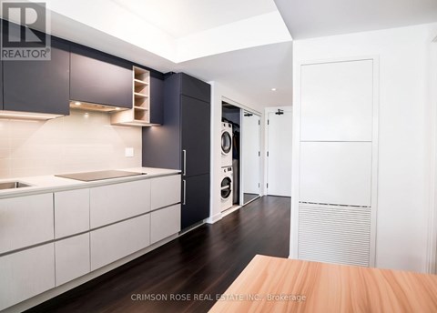 A modern kitchen with dark wood floors and white cabinetry.