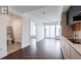 A spacious kitchen and living room with dark wood floors and white walls.