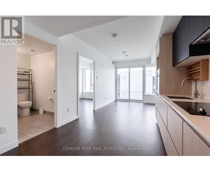 A spacious kitchen and living room with dark wood floors and white walls.