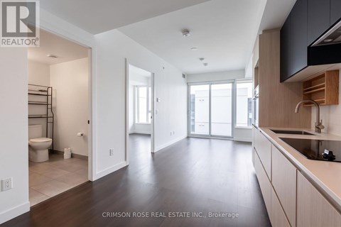 A spacious kitchen and living room with dark wood floors and white walls.