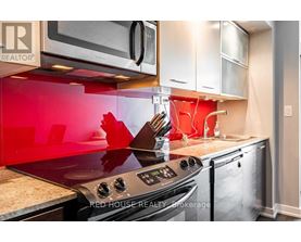 A modern kitchen with a red backsplash and stainless steel appliances.