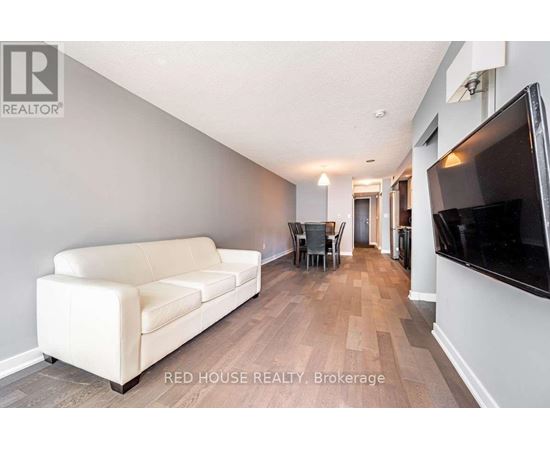 A living room with a white couch and a television on the wall.