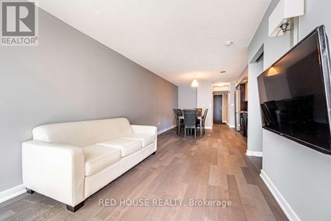 A living room with a white couch and a television on the wall.