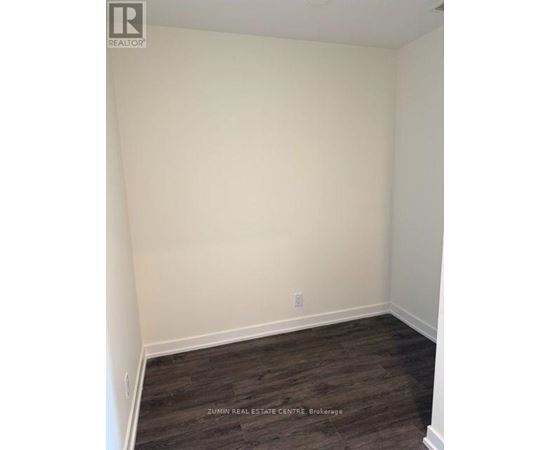 A room with white walls and dark wood flooring.