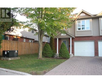 A house with a garage and a tree in front.