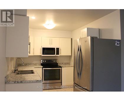 A kitchen with a refrigerator, microwave, oven, and sink.