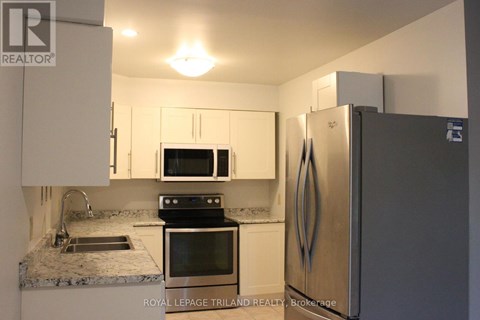 A kitchen with a refrigerator, microwave, oven, and sink.