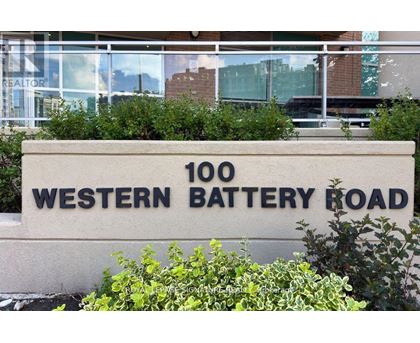 A sign that says "100 Western Battery Road" in front of some bushes.