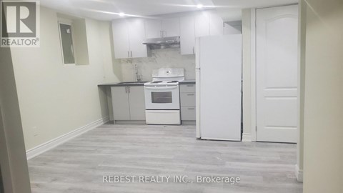 A kitchen with a white fridge and oven, and a white door.