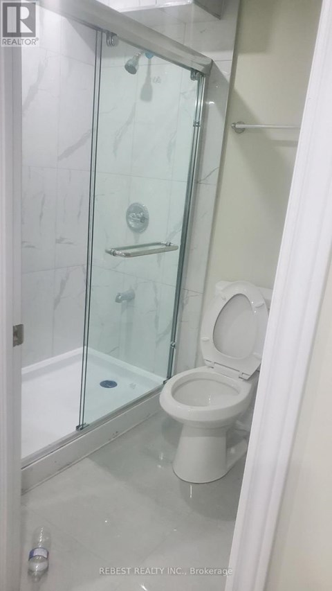 A white toilet in a glass shower stall.