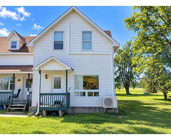 A white house with a green porch and a red door.