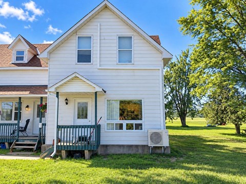 A white house with a green porch and a red door.