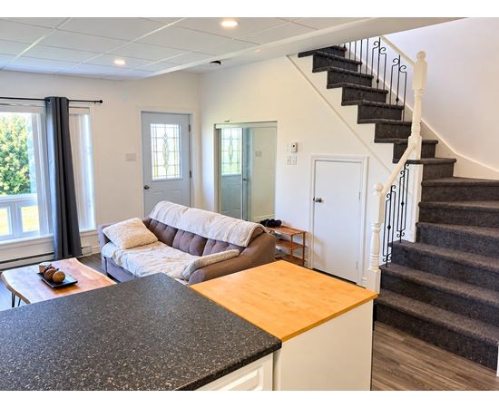 A living room with a couch, a coffee table, and a staircase.