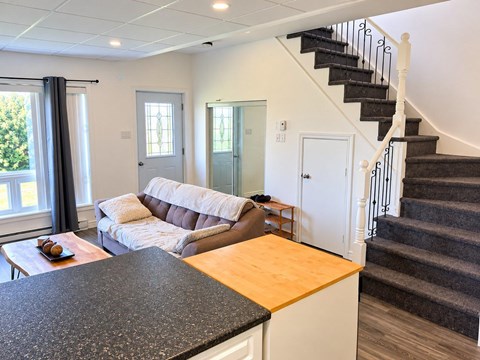 A living room with a couch, a coffee table, and a staircase.