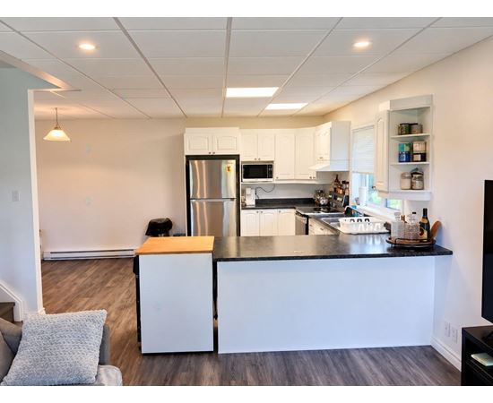 A kitchen with white cabinets and a black countertop.