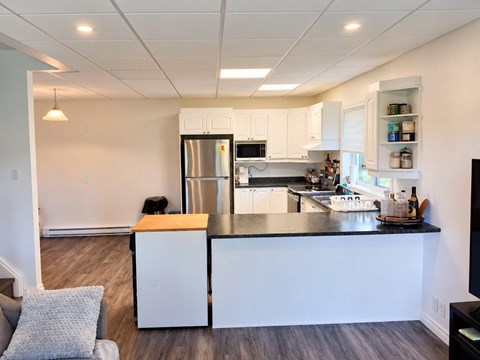 A kitchen with white cabinets and a black countertop.