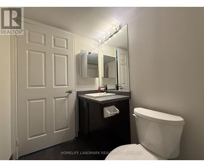 A bathroom with a toilet, sink, and mirror.