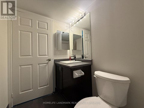 A bathroom with a toilet, sink, and mirror.
