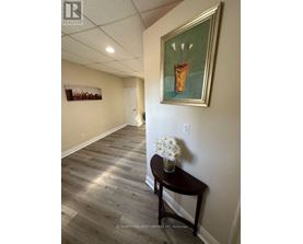 A hallway with a painting on the wall and a table with flowers on it.