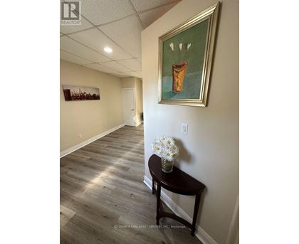 A hallway with a painting on the wall and a table with flowers on it.