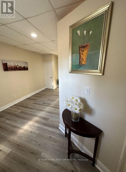 A hallway with a painting on the wall and a table with flowers on it.
