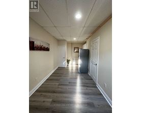 A long hallway with a refrigerator in the middle.