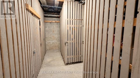 A long, narrow, unfinished room with wooden studs on the walls.