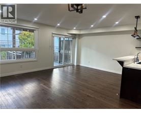 A room with wooden flooring and a large window with a view of trees and a fence.