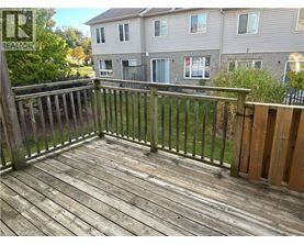 A wooden deck with a railing and a building in the background.