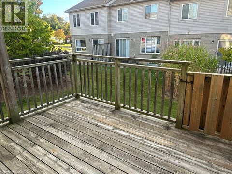 A wooden deck with a railing and a building in the background.