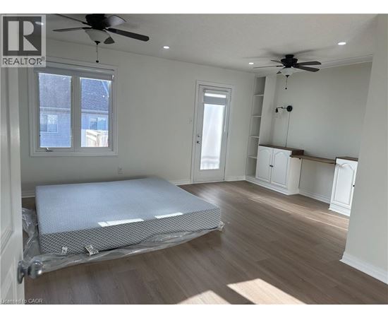 A bedroom with a bed covered in a white sheet and a ceiling fan.