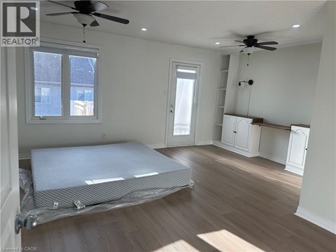 A bedroom with a bed covered in a white sheet and a ceiling fan.