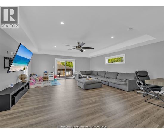 A living room with a grey sofa and a television on the wall.