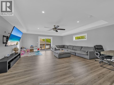 A living room with a grey sofa and a television on the wall.
