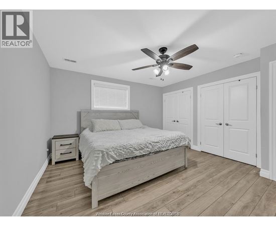 A bedroom with a bed, nightstand, and a ceiling fan.