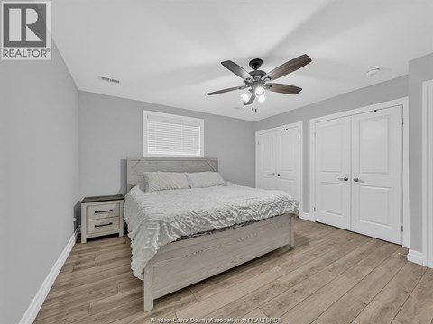 A bedroom with a bed, nightstand, and a ceiling fan.