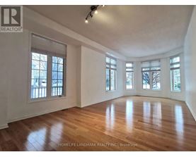 A spacious room with wooden floors and large windows.