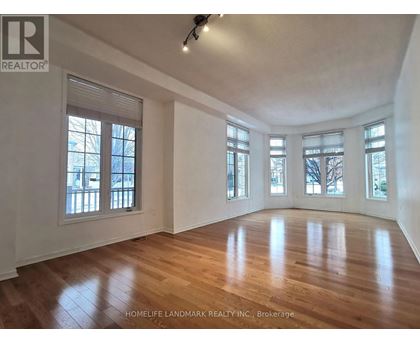 A spacious room with wooden floors and large windows.