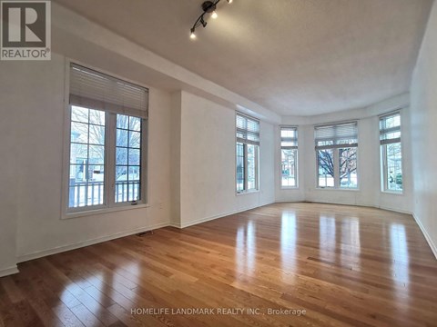 A spacious room with wooden floors and large windows.